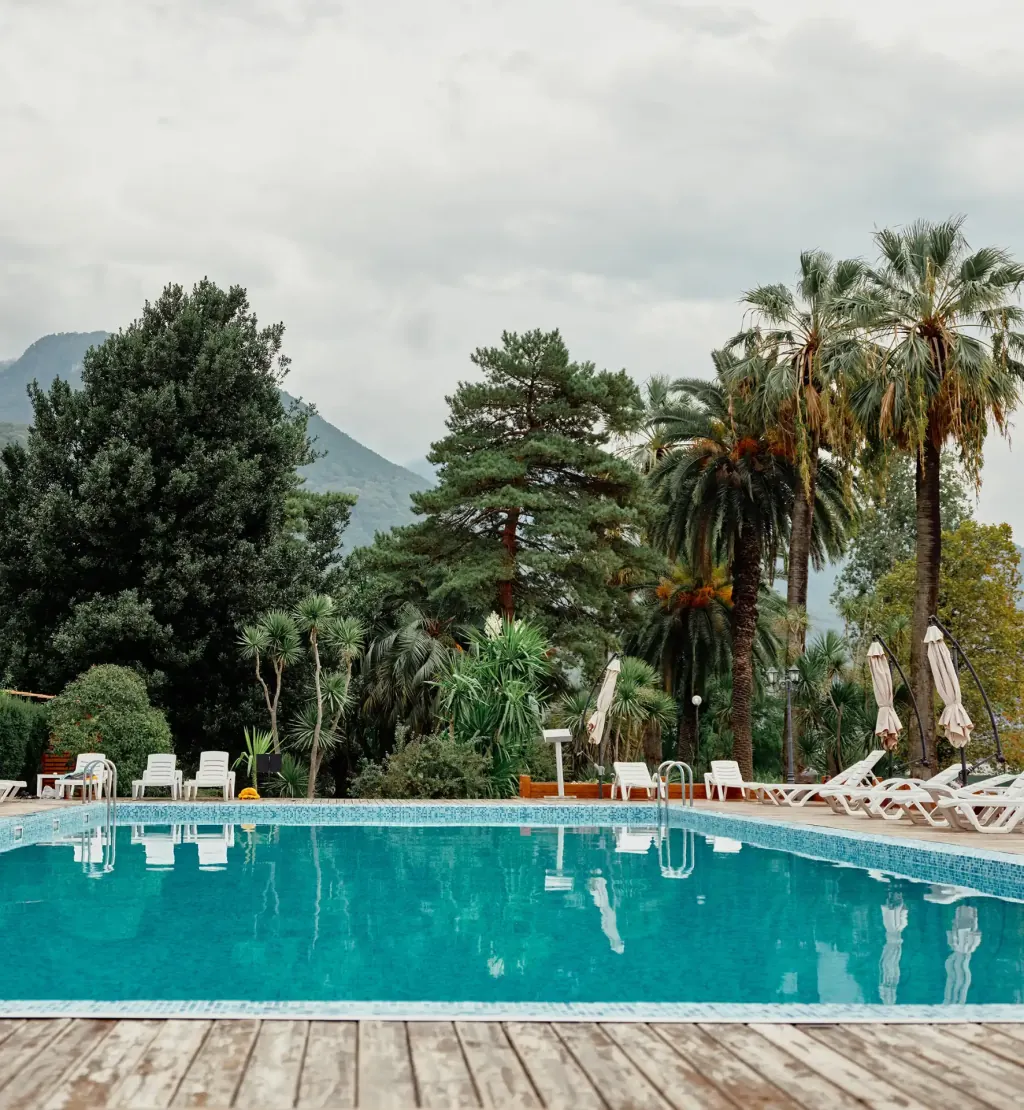 Poolterrasse mit Palmen und Bergen im Hintergrund