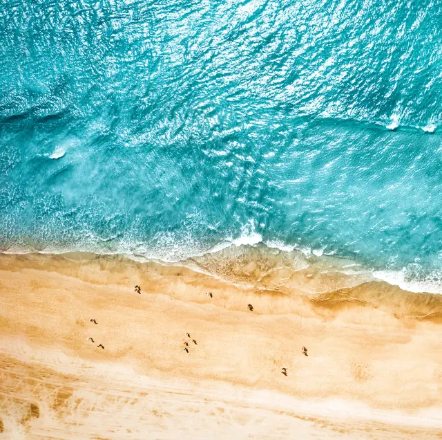 Türkises Meer und heller Sandstrand aus der Luft